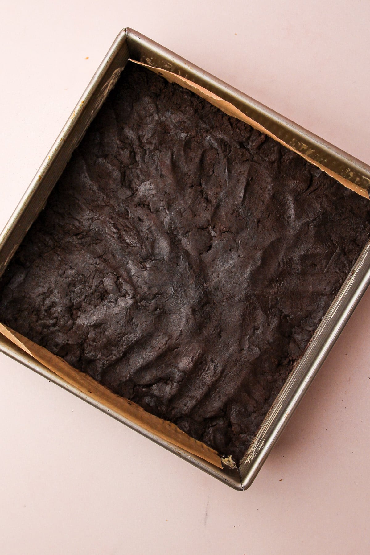 Dough for chocolate shortbread cookies pressed into a square baking pan.