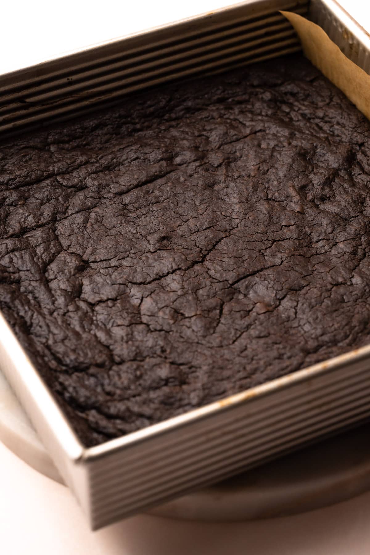 A square baking pan with baked chocolate shortbread, ready to be cut into chocolate shortbread cookies.