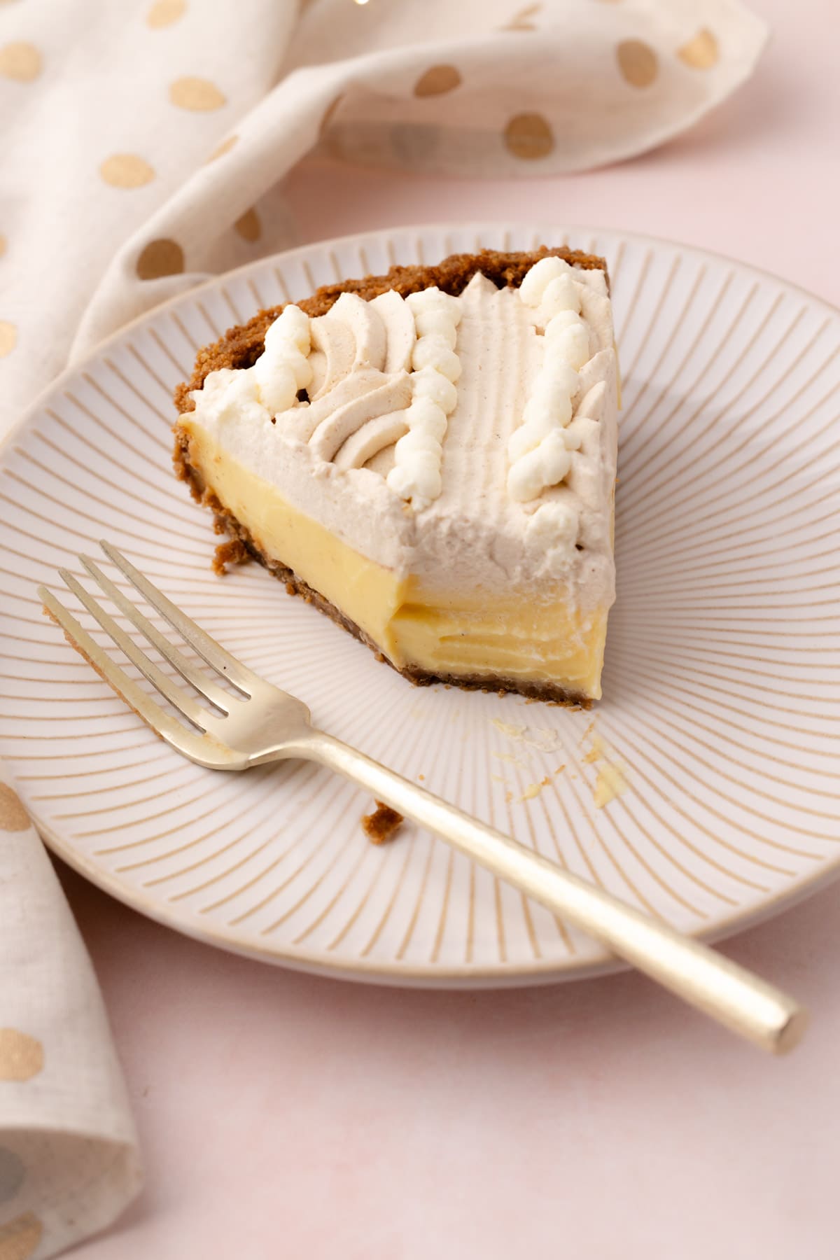 A slice of eggnog cream pie on a plate with a fork and a bite taken out of it.