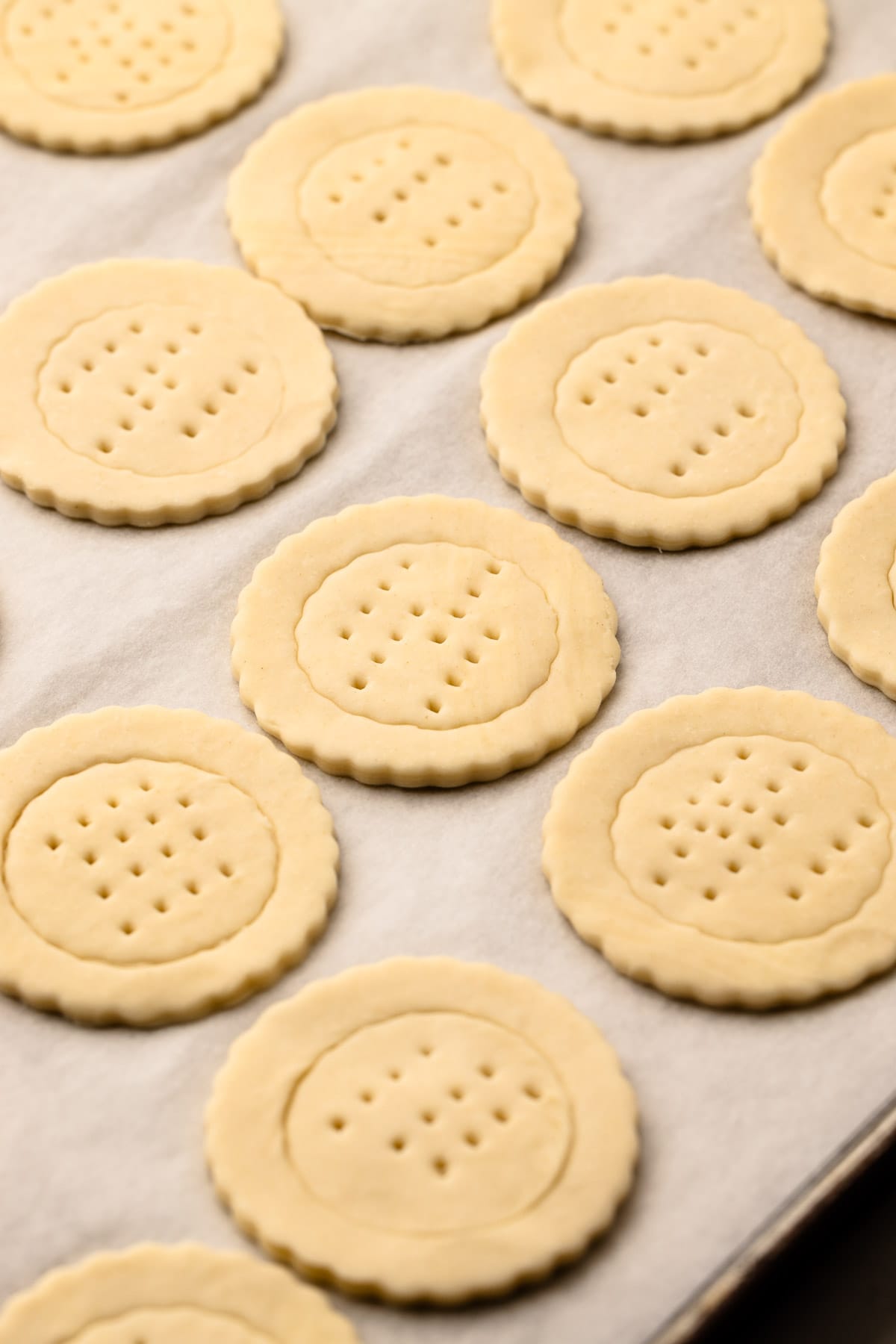 Puff pastry circles on a parchment lined sheetpan with a circle indent and fork marks in the middle.