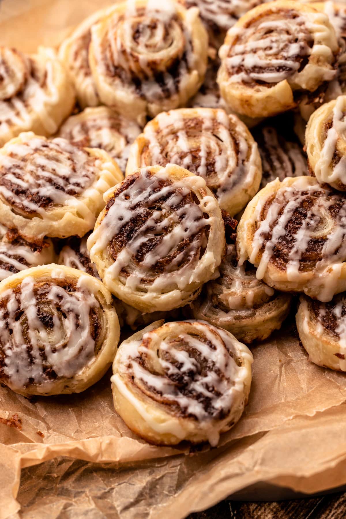 Pie crust cinnamon roll cookies baked and glazed on a serving tray.