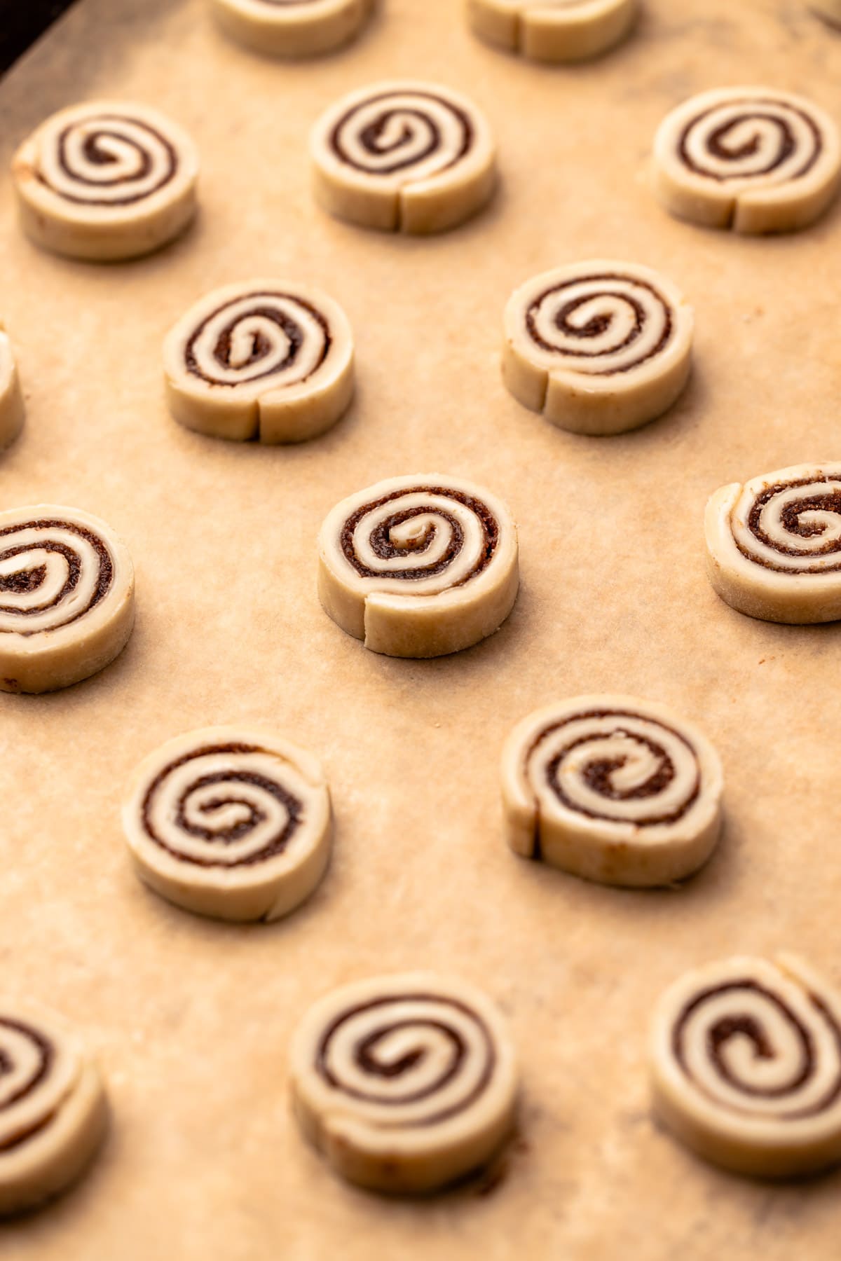 Unbaked cinnamon roll cookies on a sheet tray.