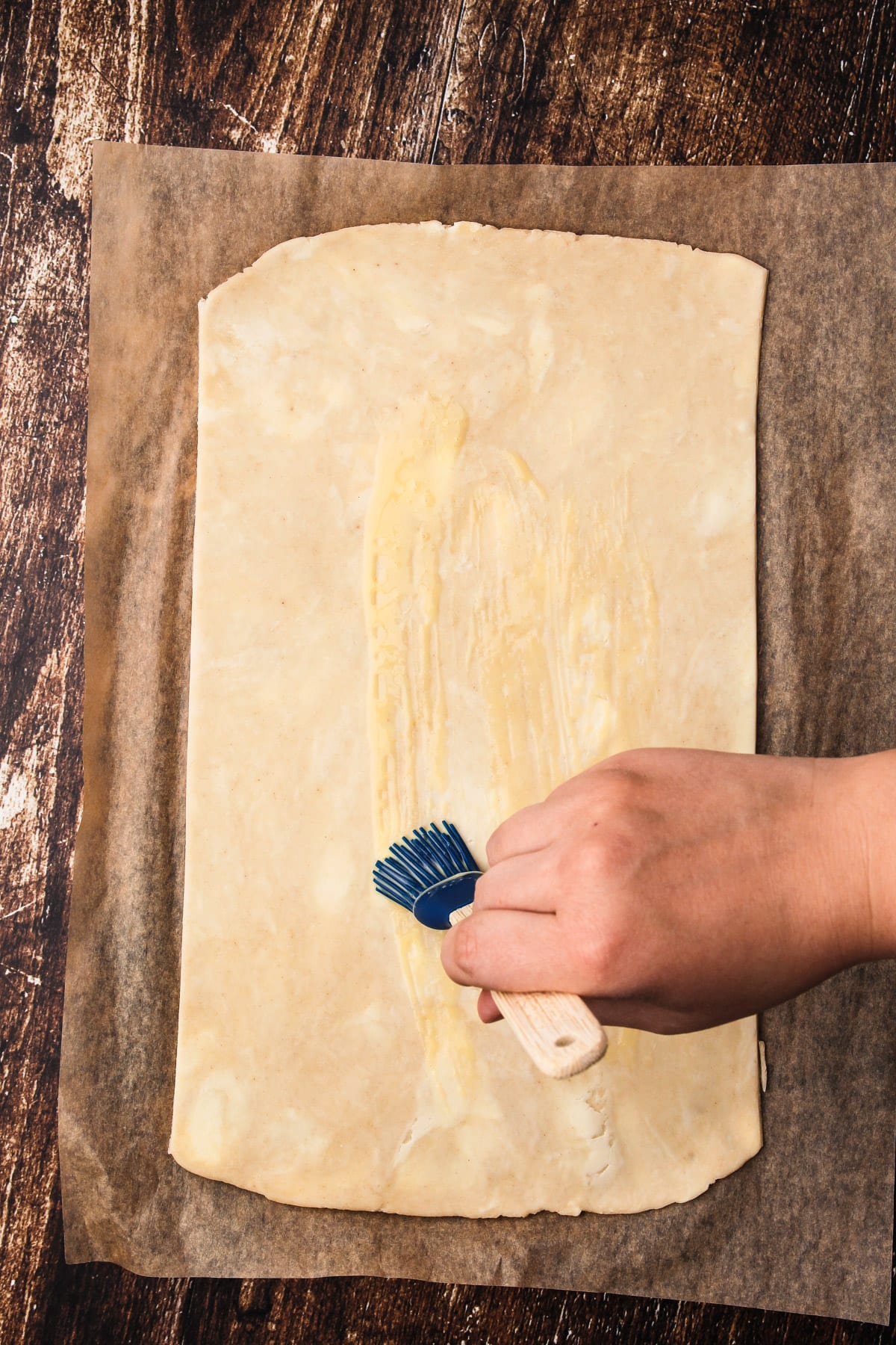 Brushing egg wash on a rectangle shaped pie dough.