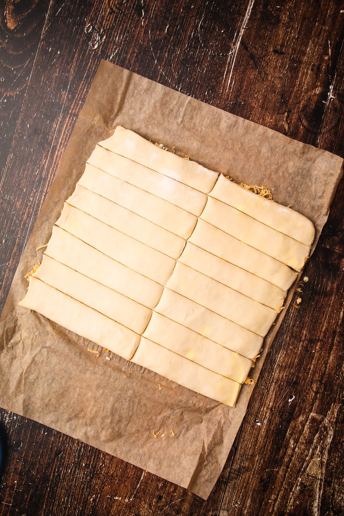 Two pieces of puff pastry with cheese in between cut into 16 strips.