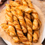 Baked puff pastry cheese twists on a platter.