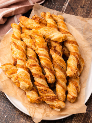 Baked puff pastry cheese twists on a platter.