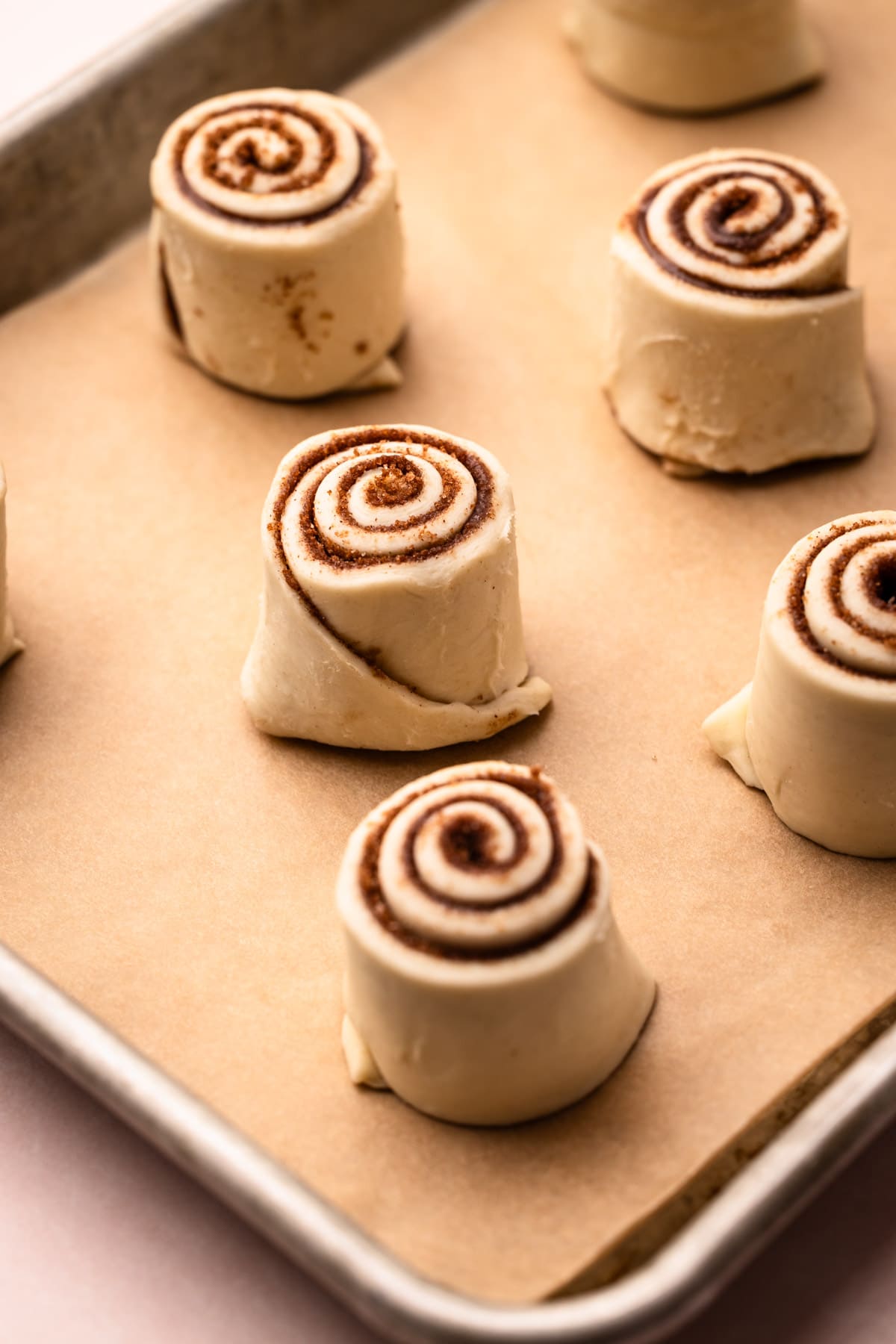 Unbaked puff pastry cinnamon rolls on a parchment-lined baking sheet.