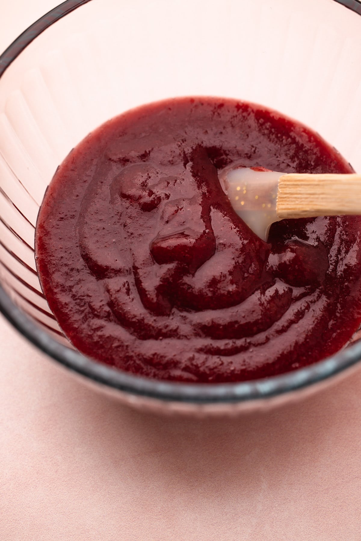 A bowl with a puree of roasted plums and a rubber spatula for mascarpone plum pie.