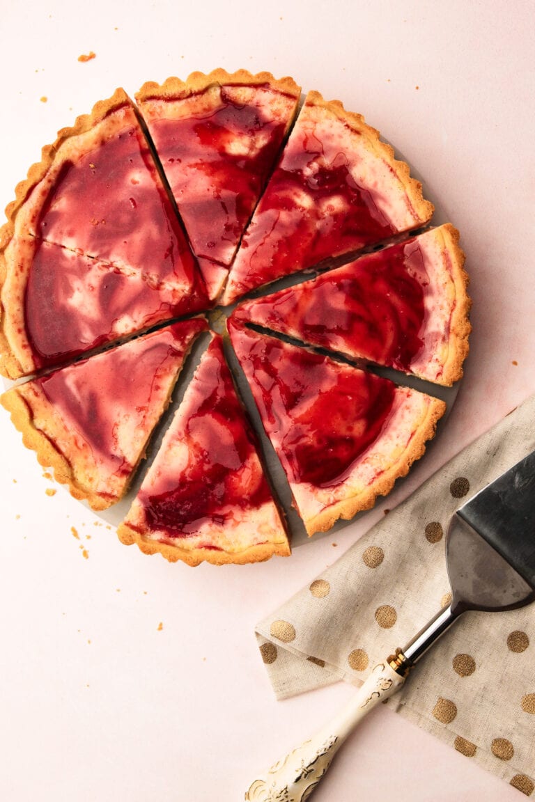 A sliced mascarpone plum pie with a pie server next to it.