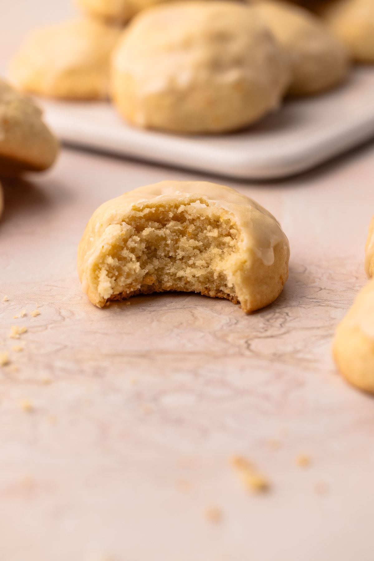 A bitten soft orange cookie with icing to reveal a moist crumb.