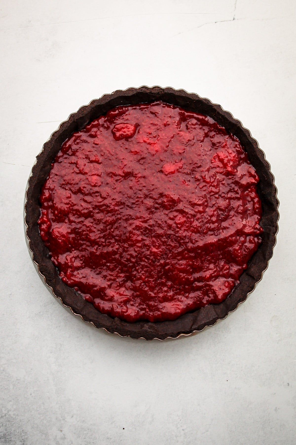 A baked chocolate tart shell filled with strawberry filling for strawberry chocolate pie.