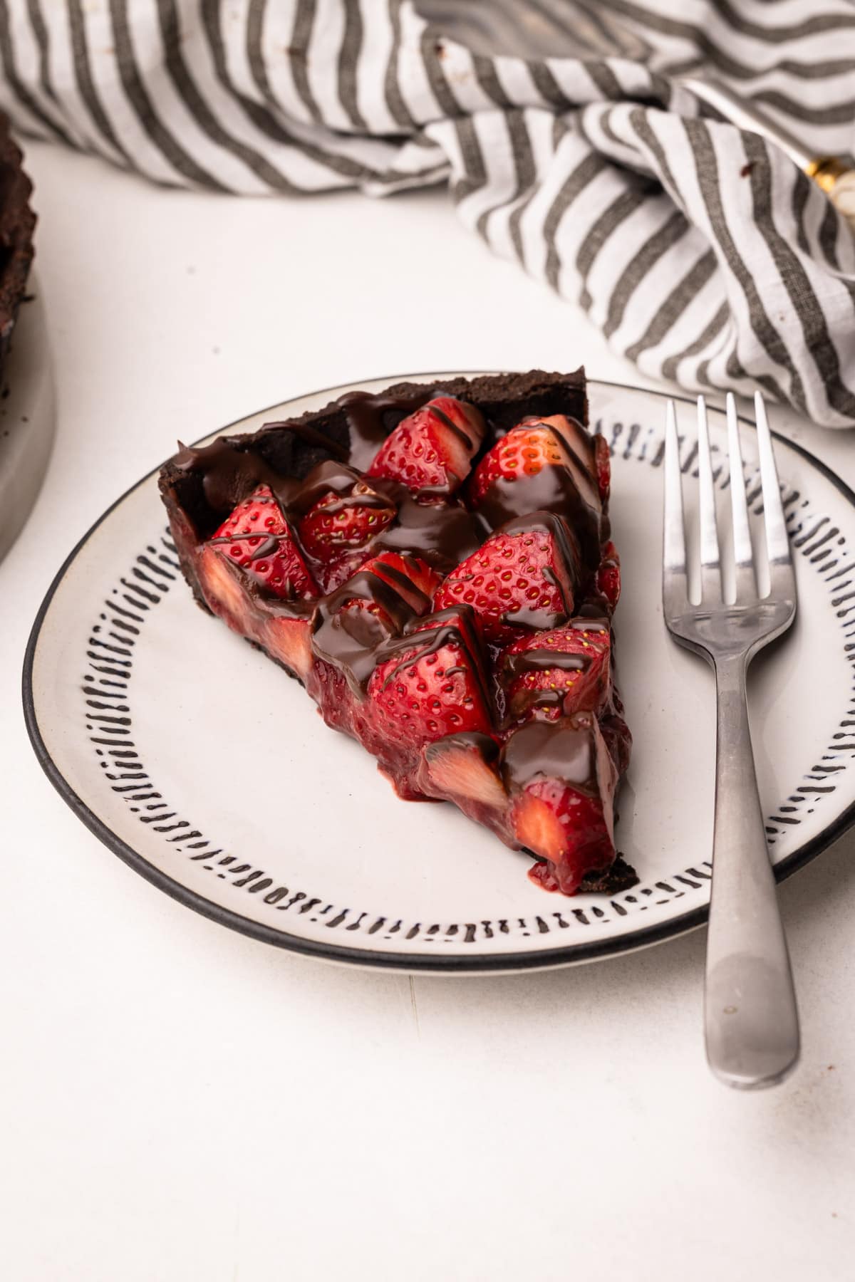 A slice of chocolate strawberry pie on a plate with a fork.