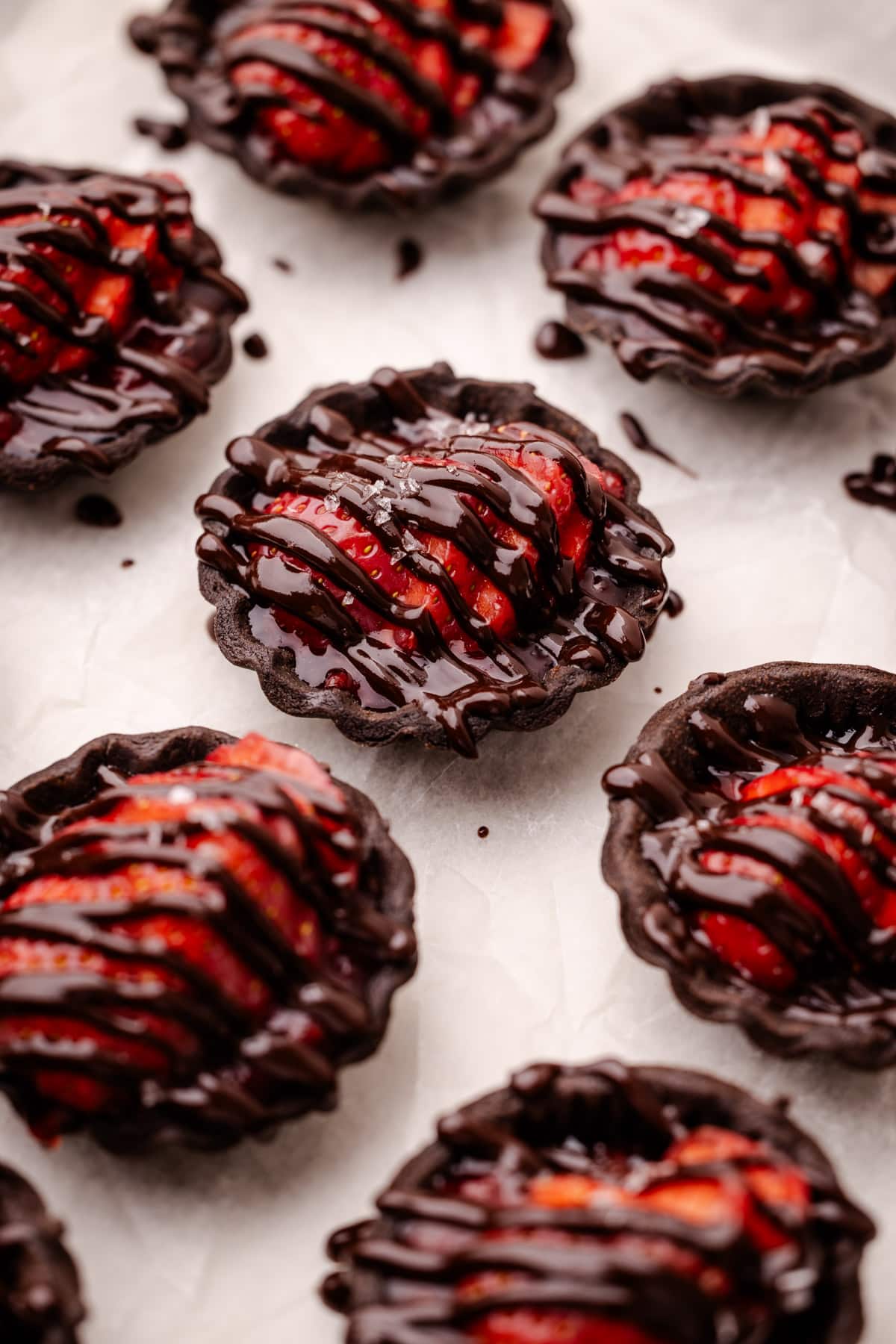 Chocolate strawberry tartlets drizzled with melted chocolate.