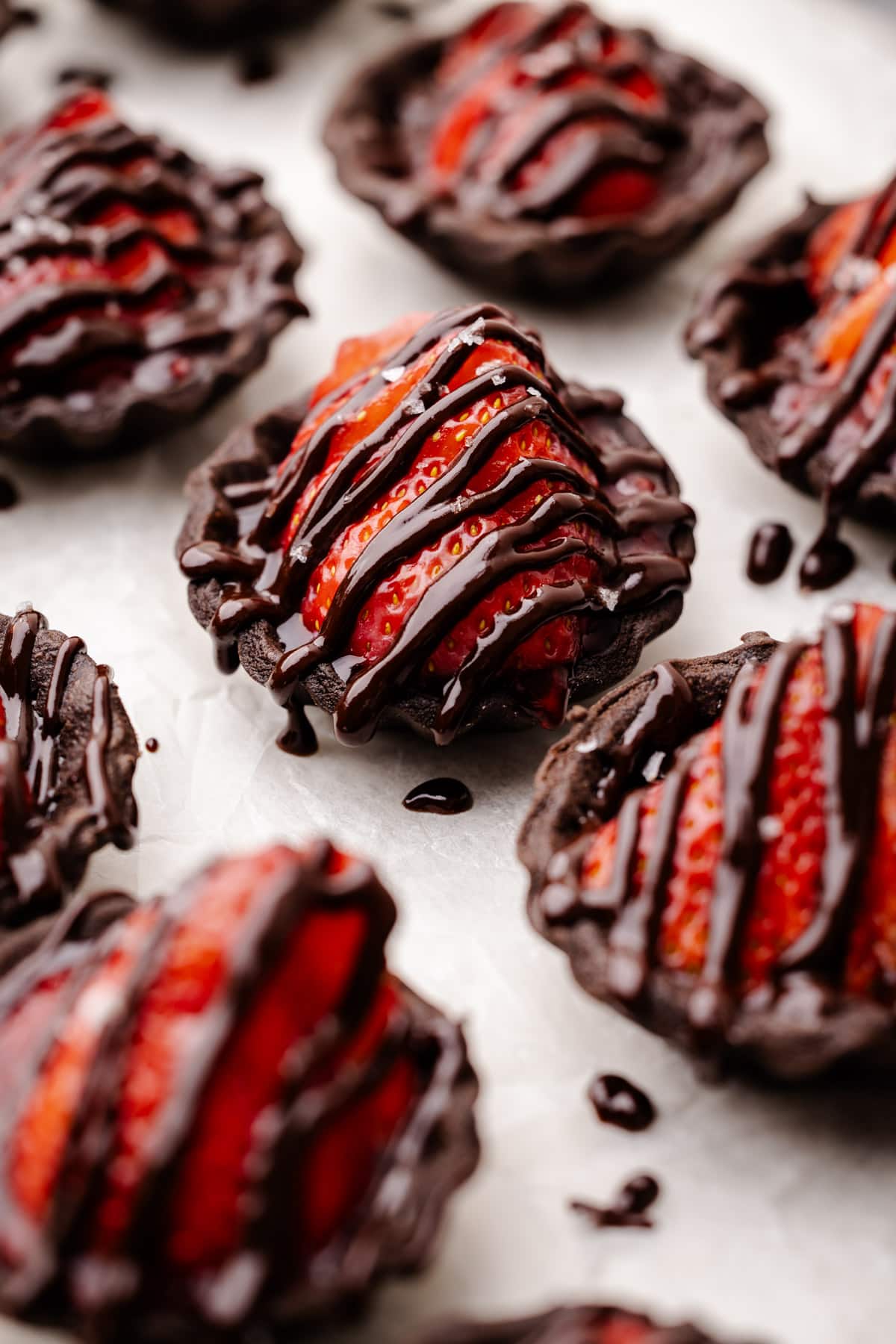 Chocolate strawberry tarts drizzled with melted chocolate.