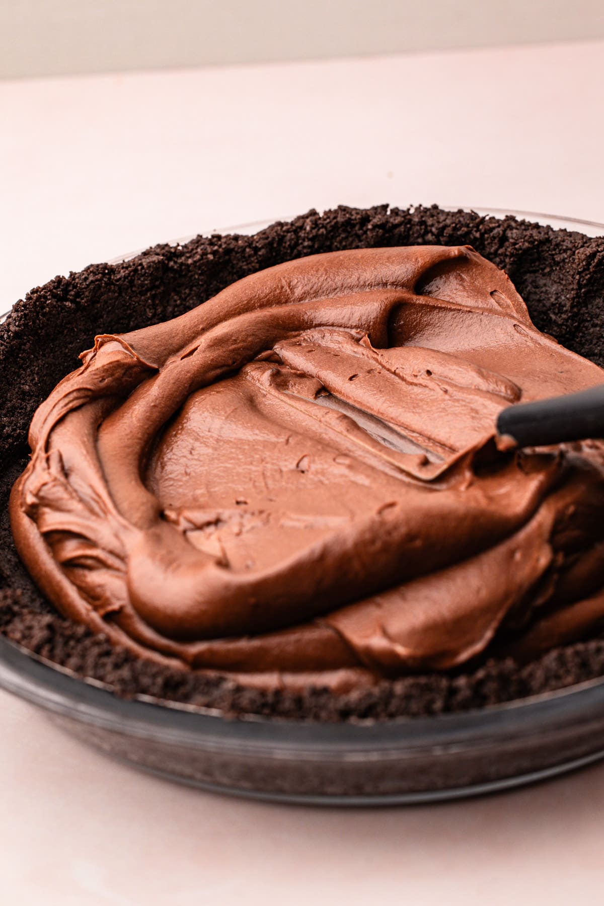 Chocolate filling being spread into a chocolate crumb crust for easy chocolate pie.