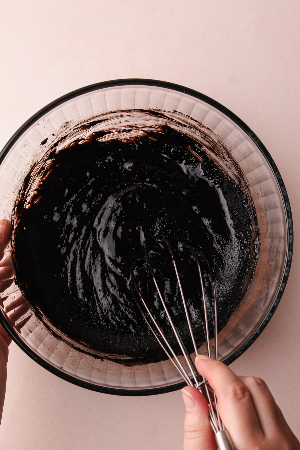 Whisking together almond flour brownies in a glass bowl.