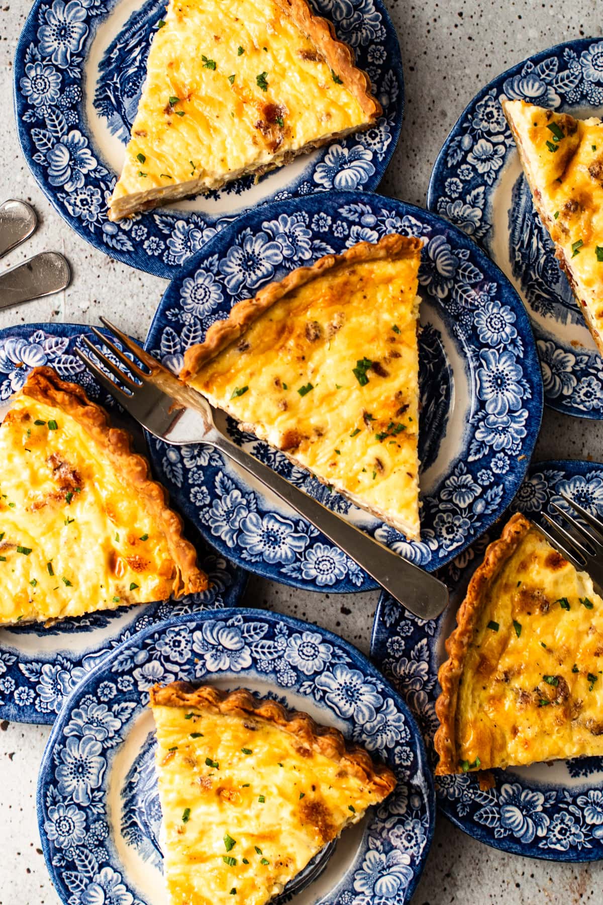 Many slices of quiche lorraine on bright blue plates.