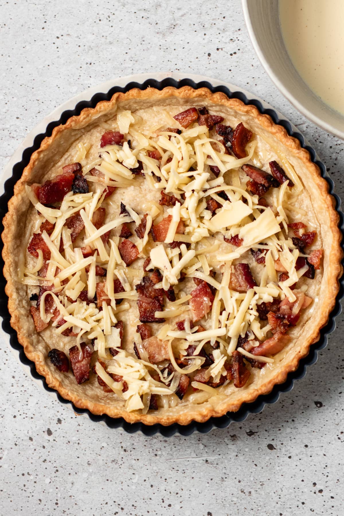 A blind baked pie shell with crispy bacon and cheese in it.