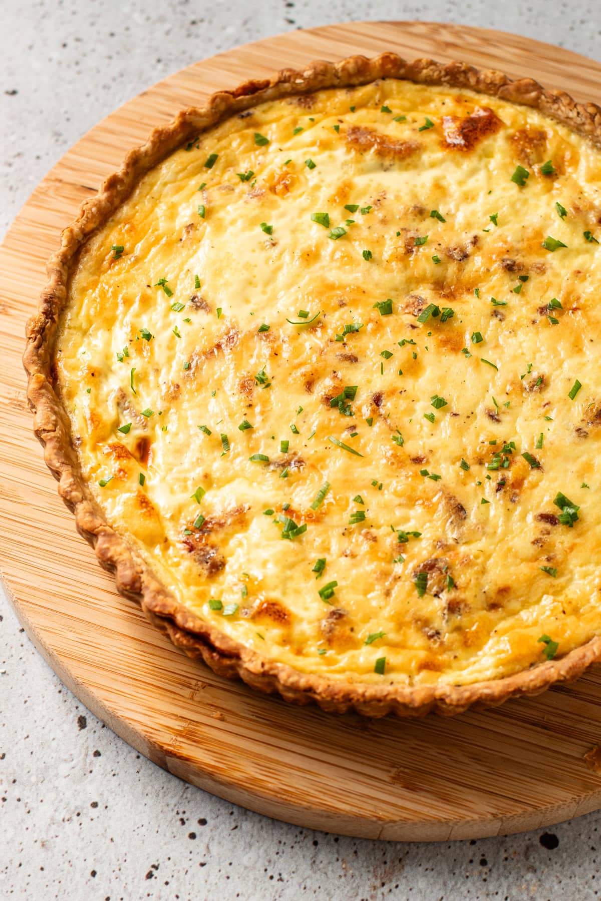 A baked quiche lorraine with a sprinkle of chives.