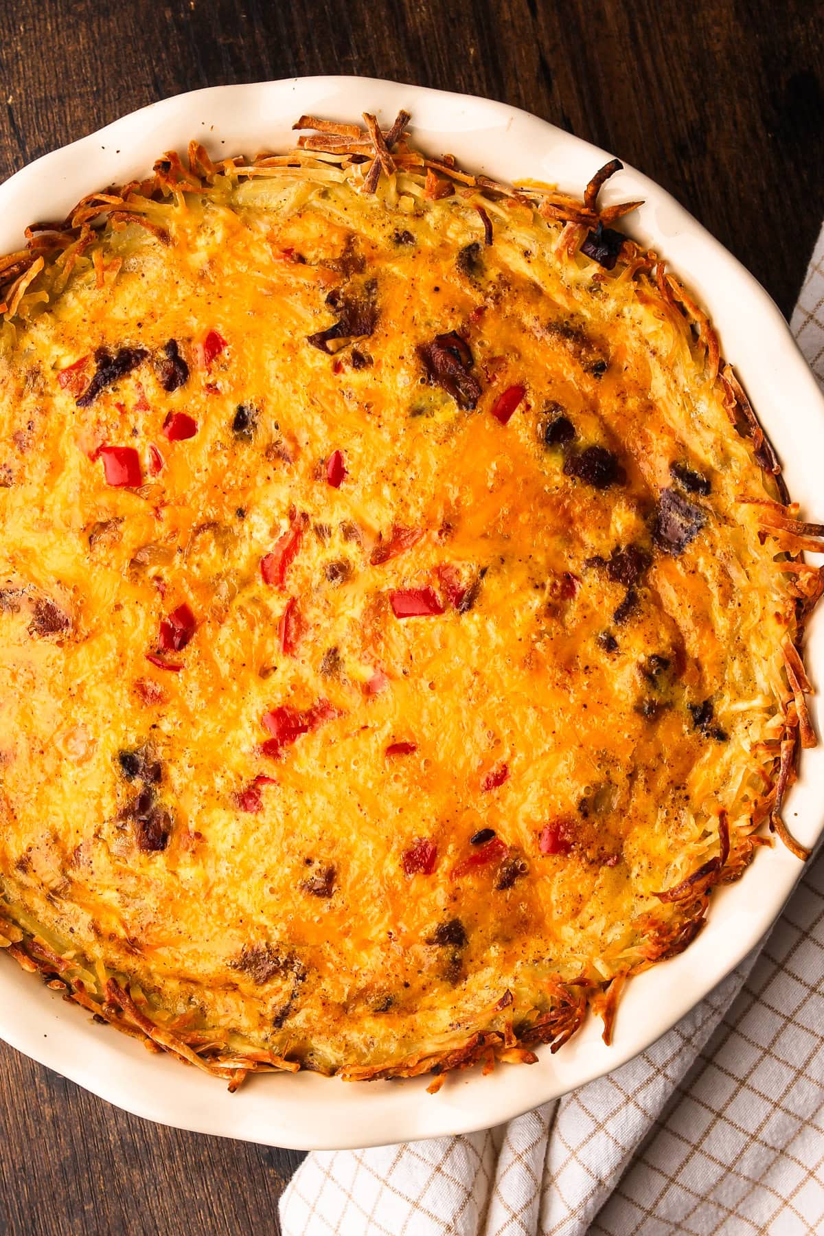 A fully baked breakfast pie with a hashbrown crust and bacon, eggs, onions and cheese.