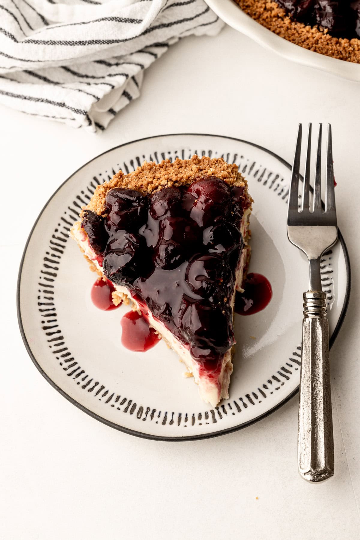 A slice of cherry cheesecake pie on a plate with a fork.