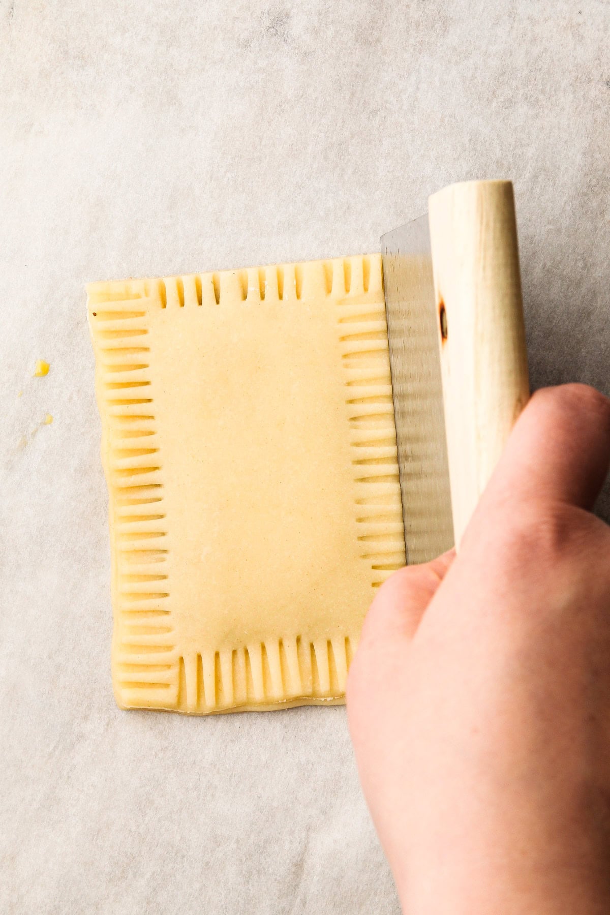 Cutting a piece of pop tart dough to seal the edges.