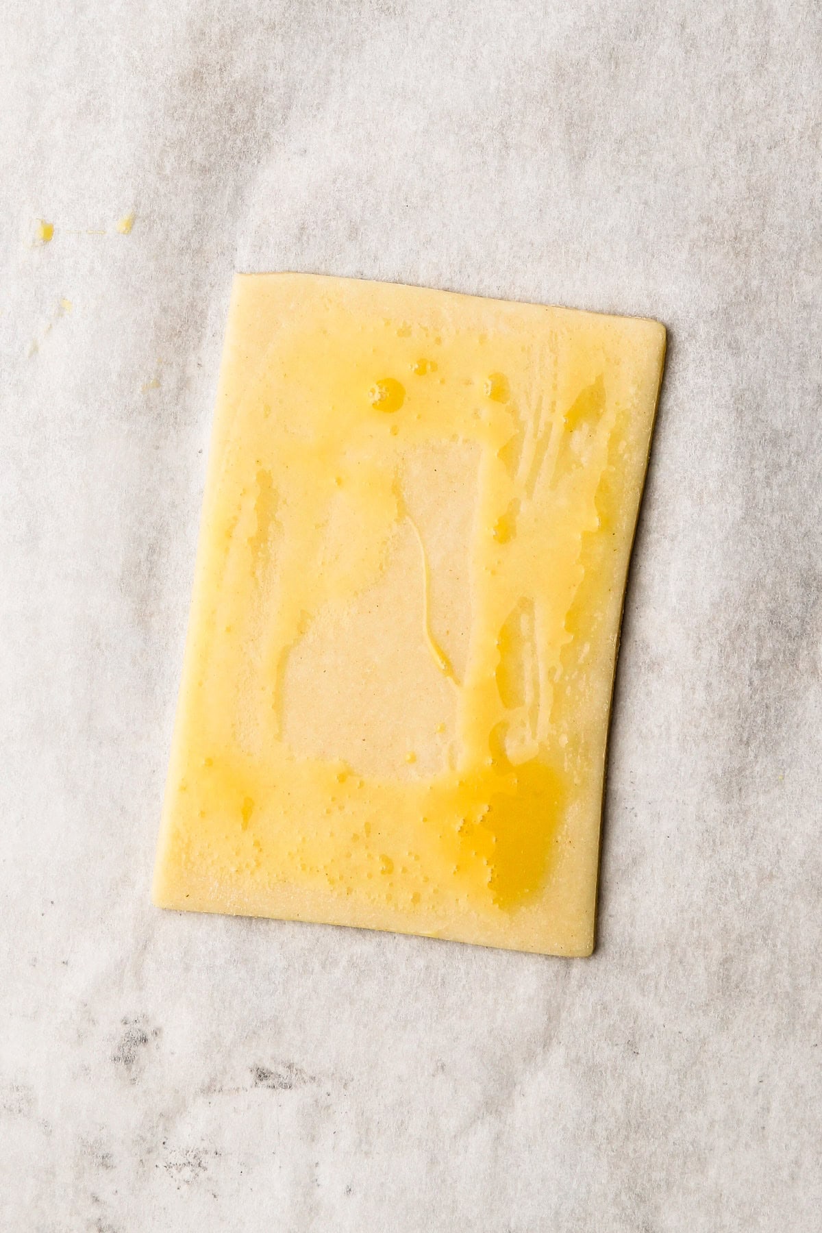 A rectangle pastry with egg wash on it.