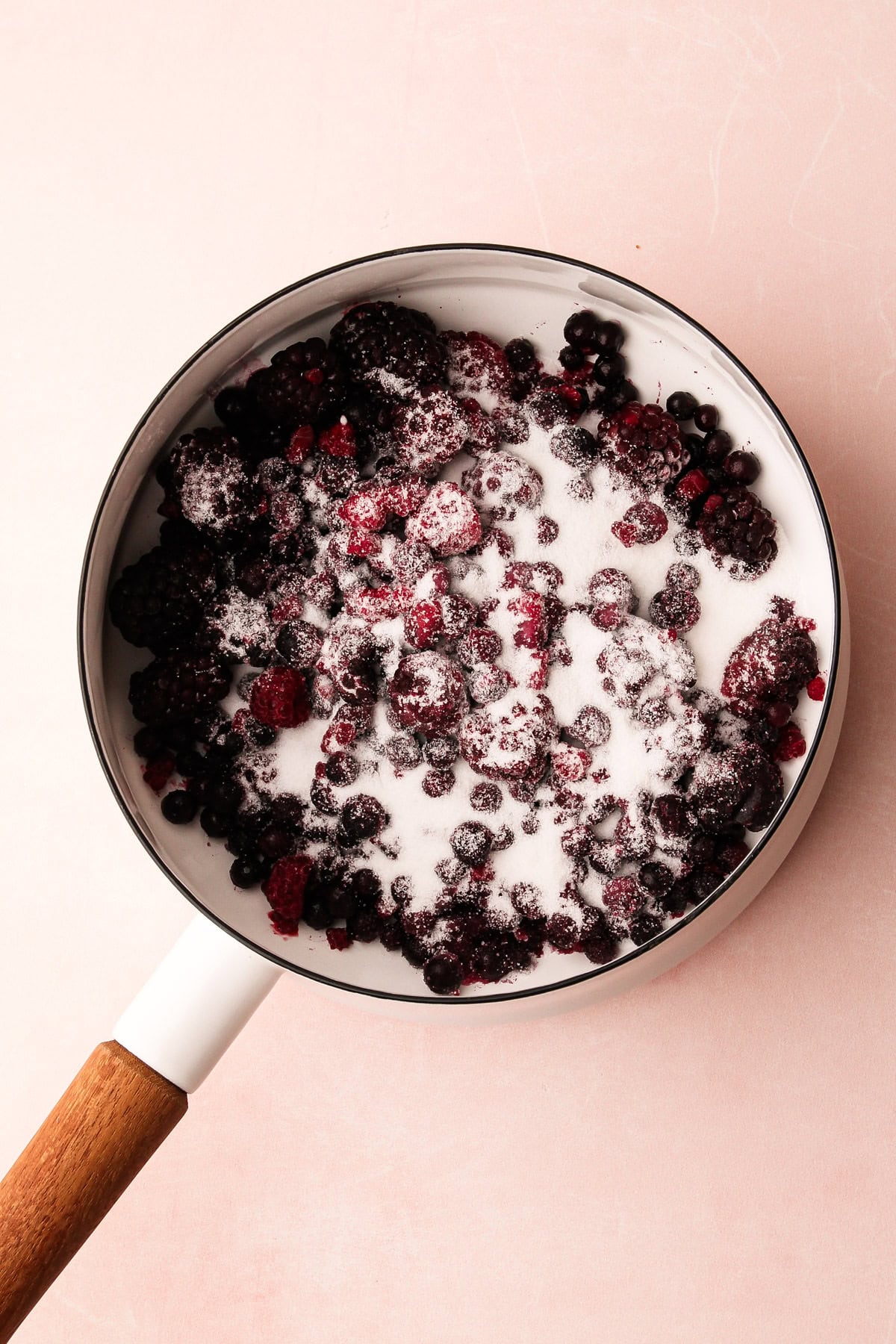 Mixed berries and sugar in a pot.