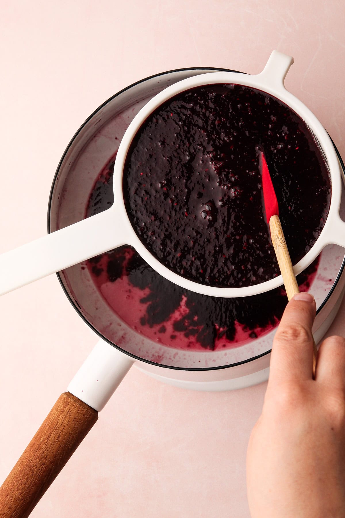 Straining cooked berries into a pot.