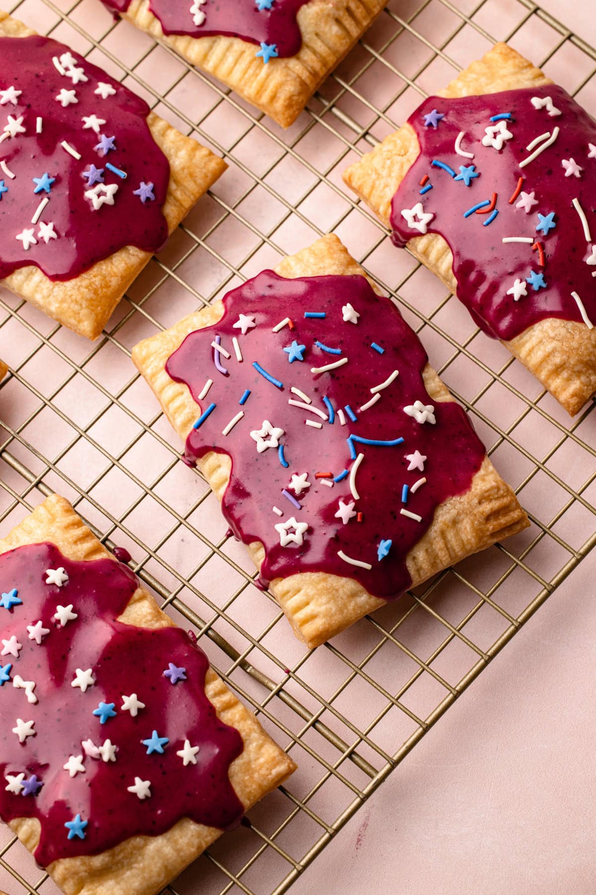 Homemade wild berry pop tarts decorated on a cooling rack.