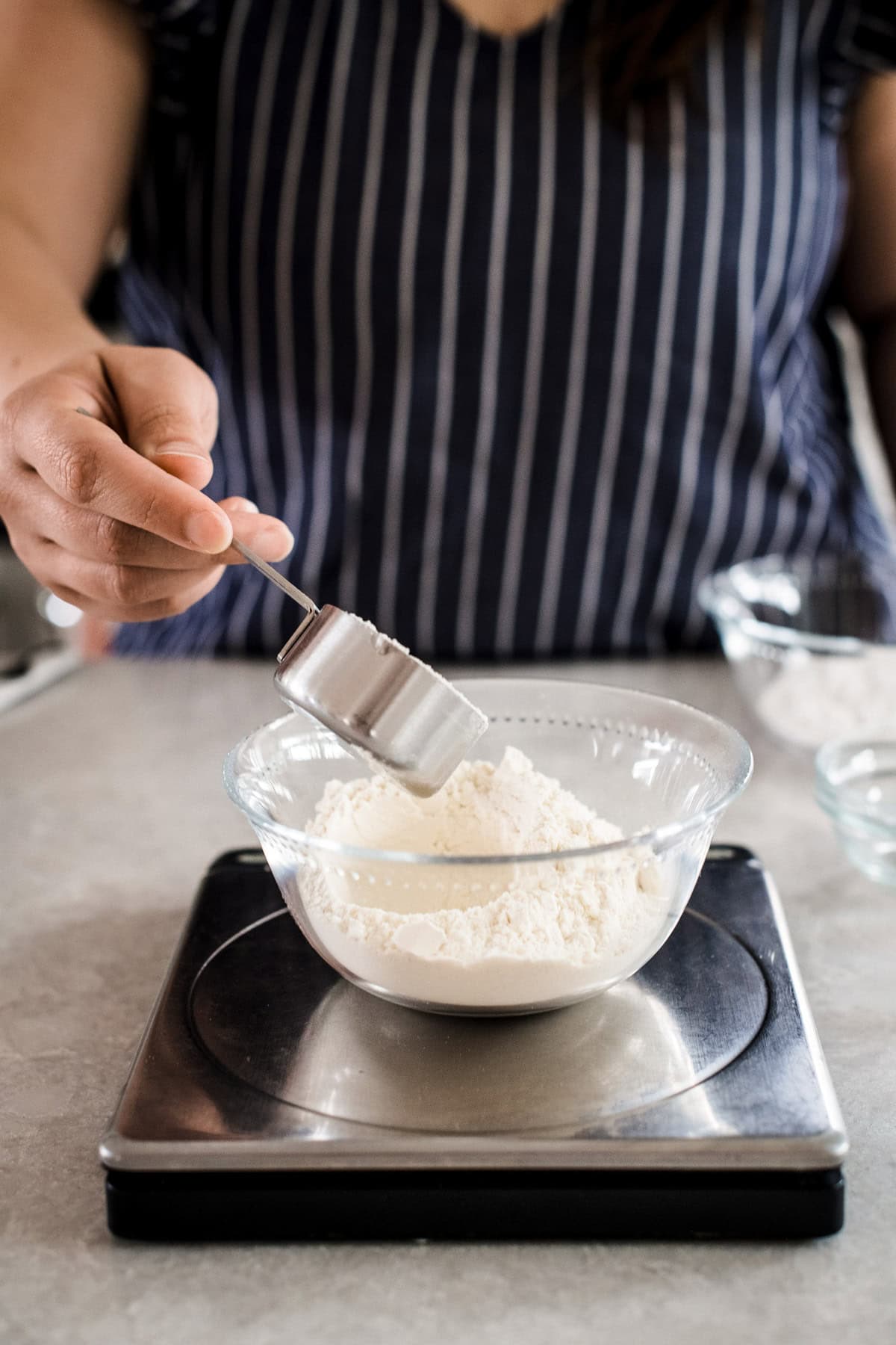 A baker measuring out flour on a digital scale.