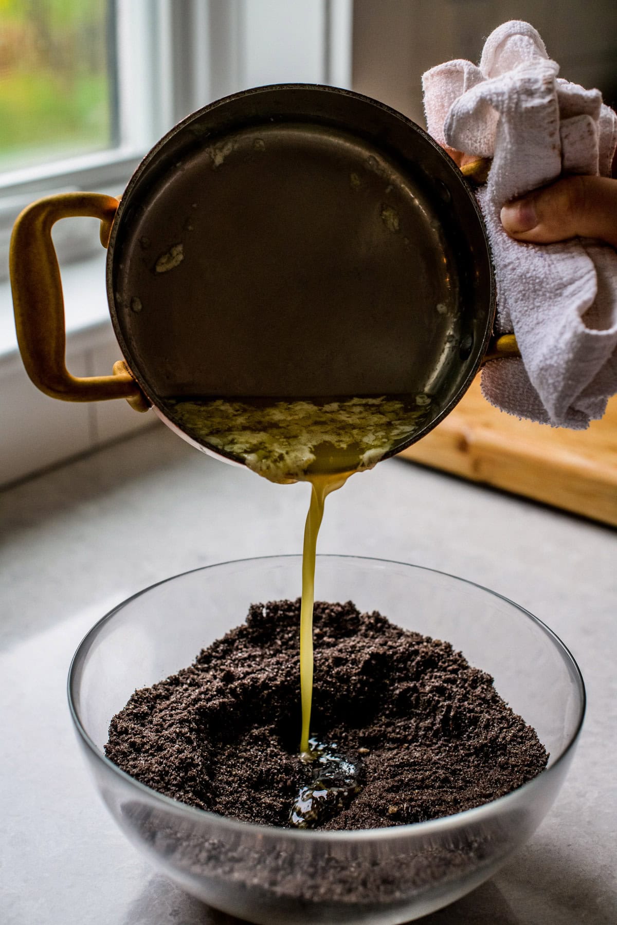 Butter being poured into a chocolate crumb mixture.