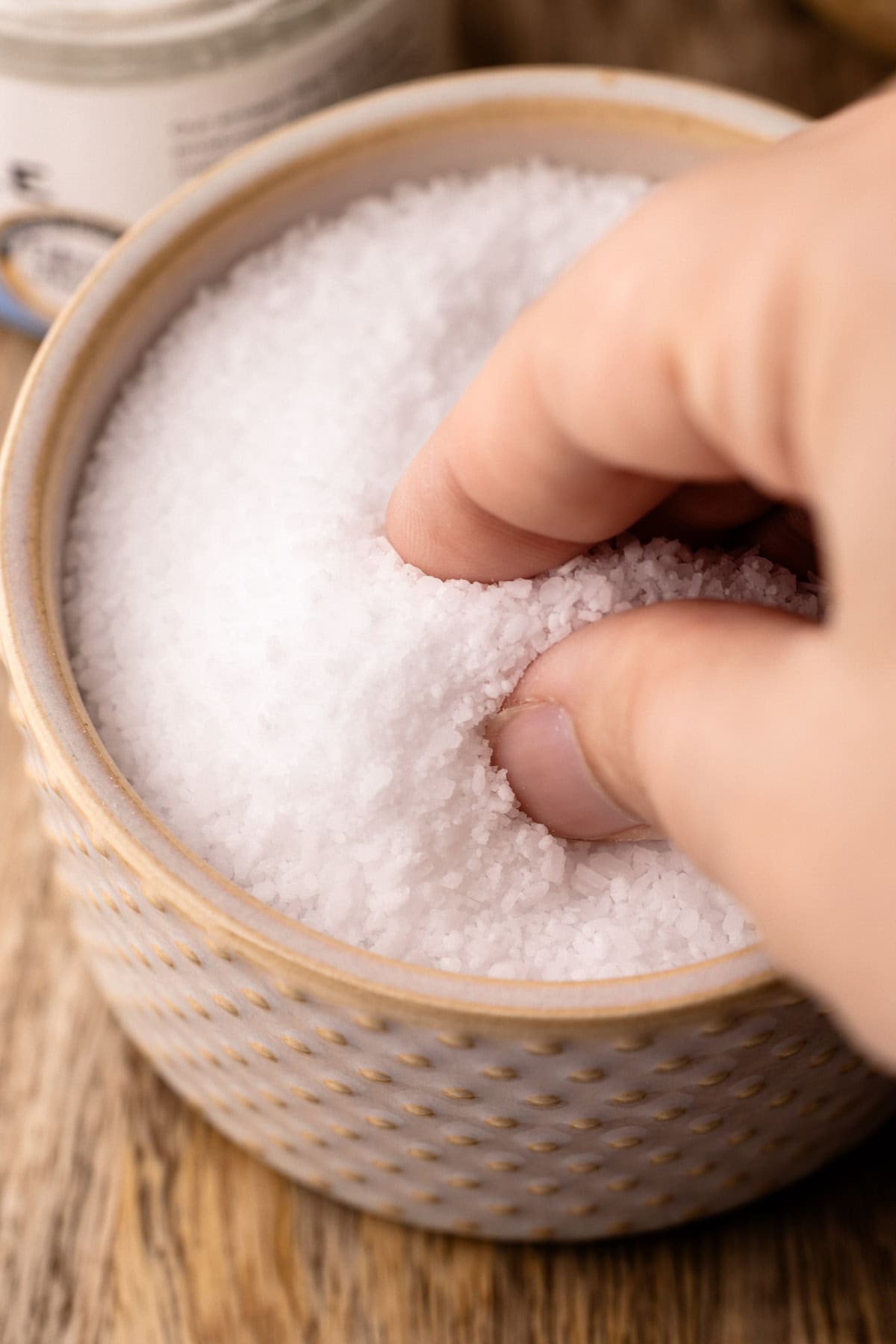 Grabbing a pinch of salt from a small container.