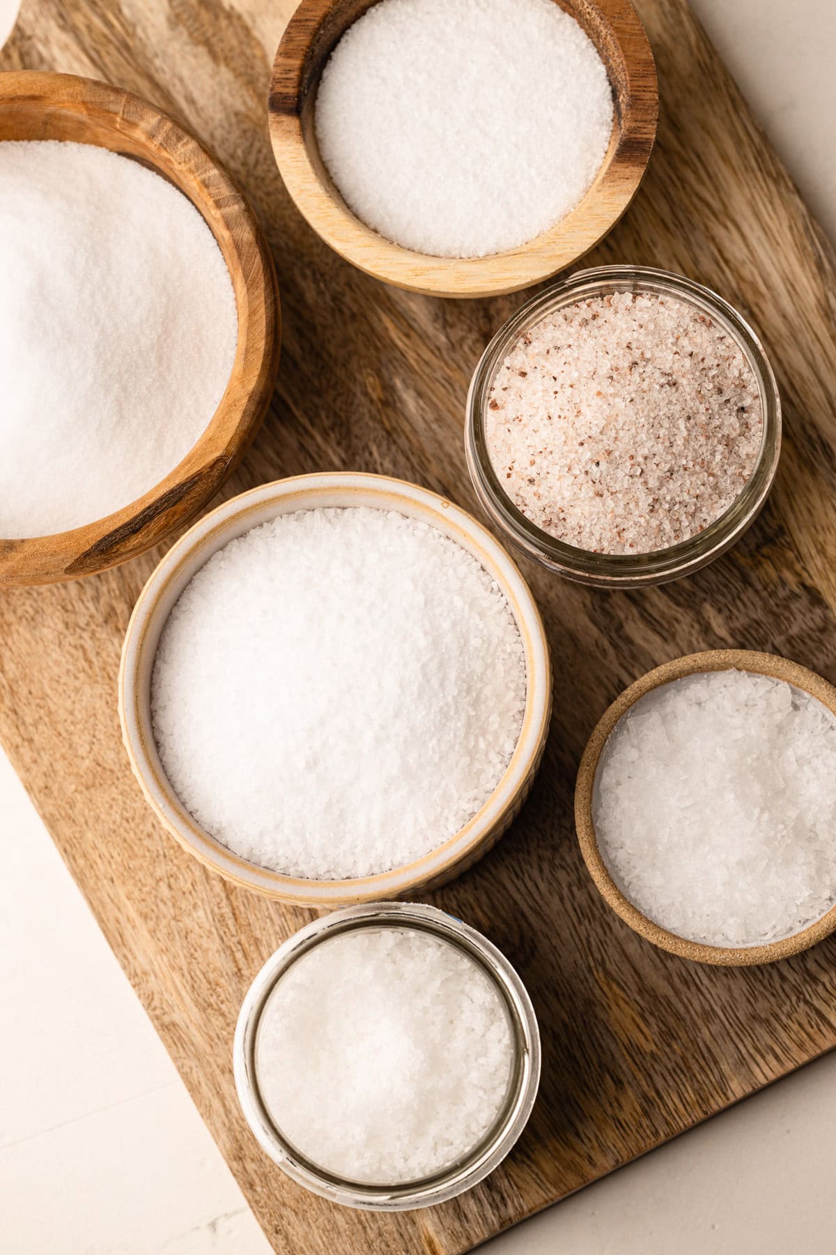 7 small bowls filled with different types of salt.