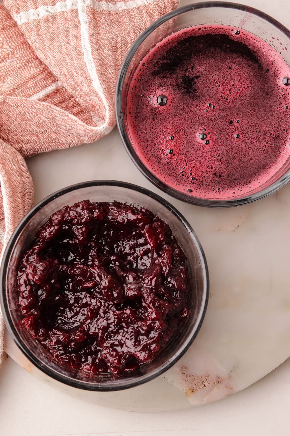 Two jars filled with separated cooked cherries and cherry juice for an ice cream recipe.