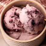 Three scoops of homemade cherry ice cream in a serving bowl.