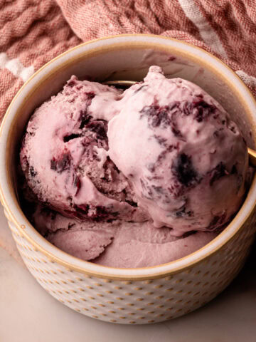 Three scoops of homemade cherry ice cream in a serving bowl.