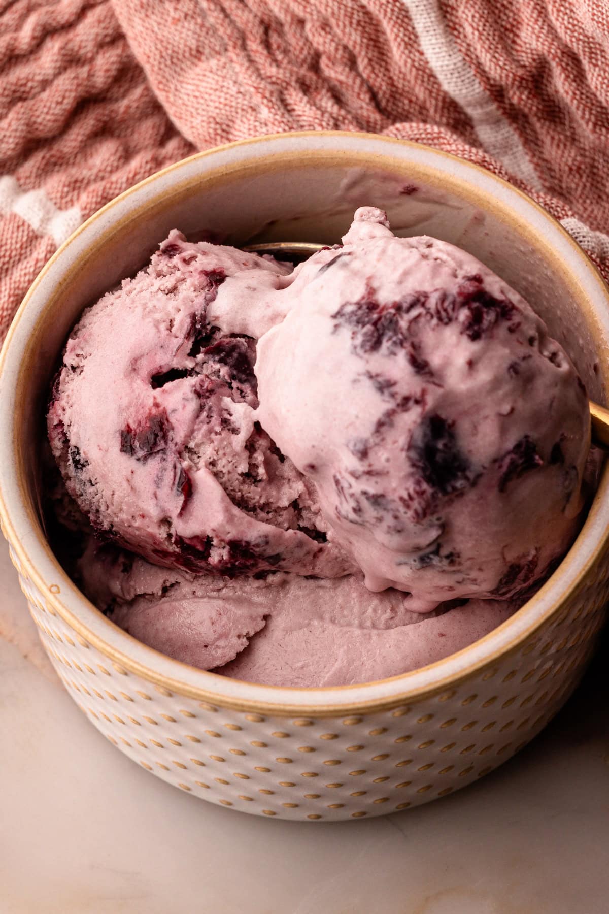 Three scoops of homemade cherry ice cream in a serving bowl.