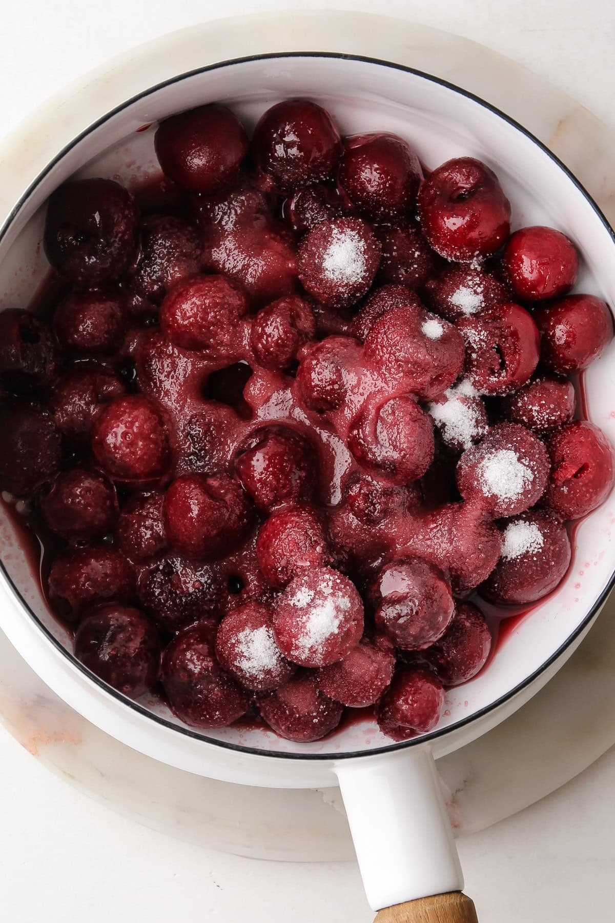 Frozen cherries in a pot with sugar.