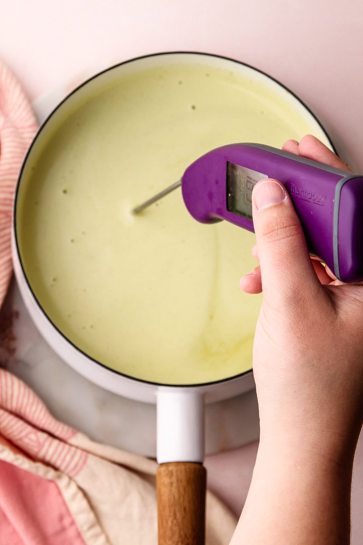 Checking the temperature with a thermometer of pistachio ice cream custard.