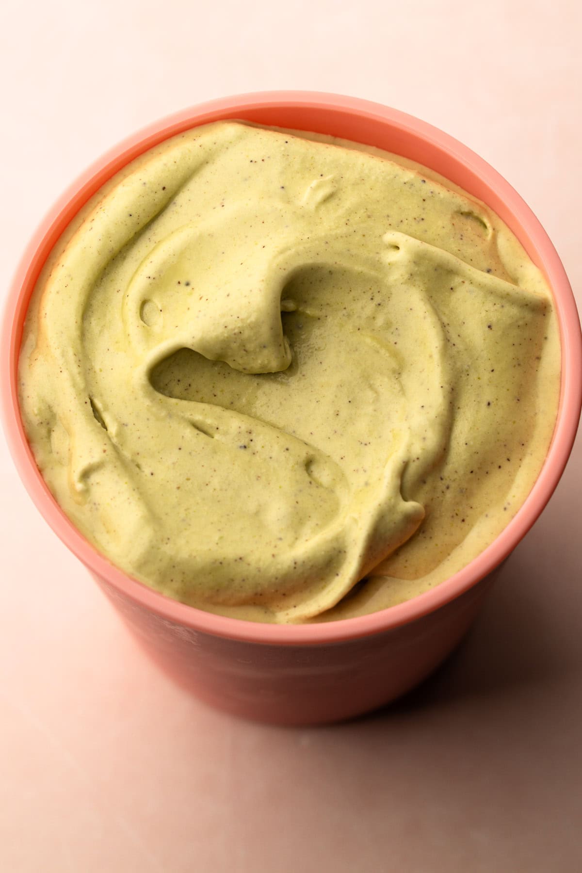 Homemade pistachio ice cream in a pink container.