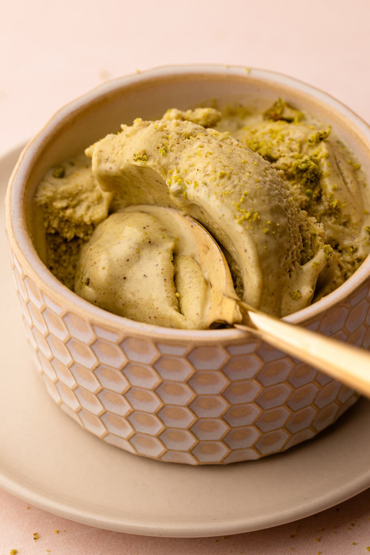 A serving of pistachio ice cream with a sprinkle of pistachios on top in a small bowl.