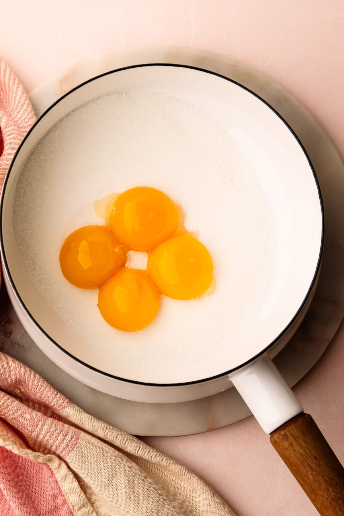 Four egg yolks in a pot of sugar.