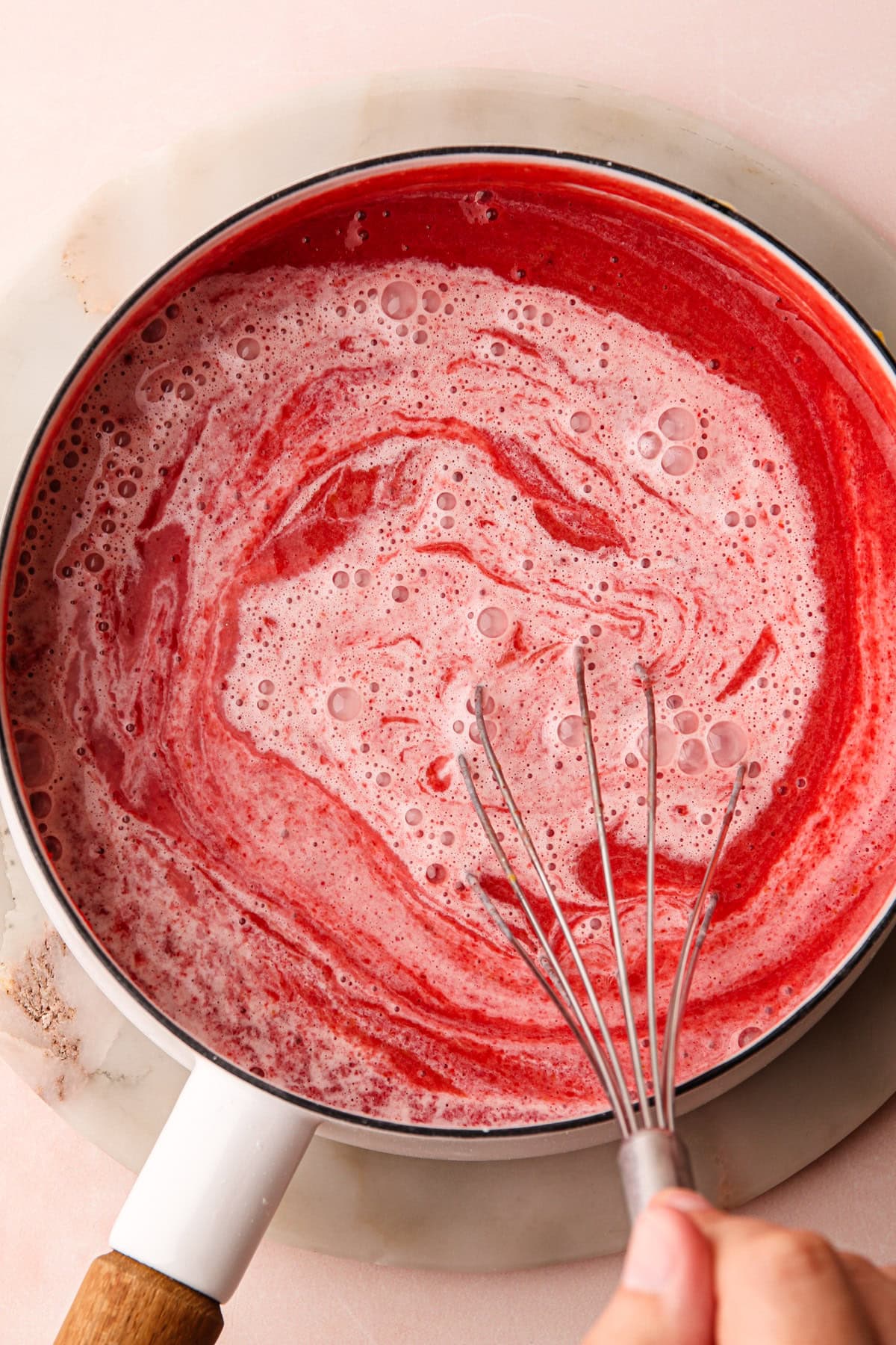 Whisking together strawberry pudding ingredients in a pot.