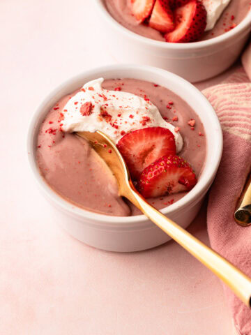 A serving of stovetop strawberry pudding made from scratch with cream and fresh strawberries.