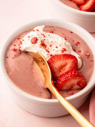 A serving of strawberry pudding with whipped cream and fresh sliced strawberries.