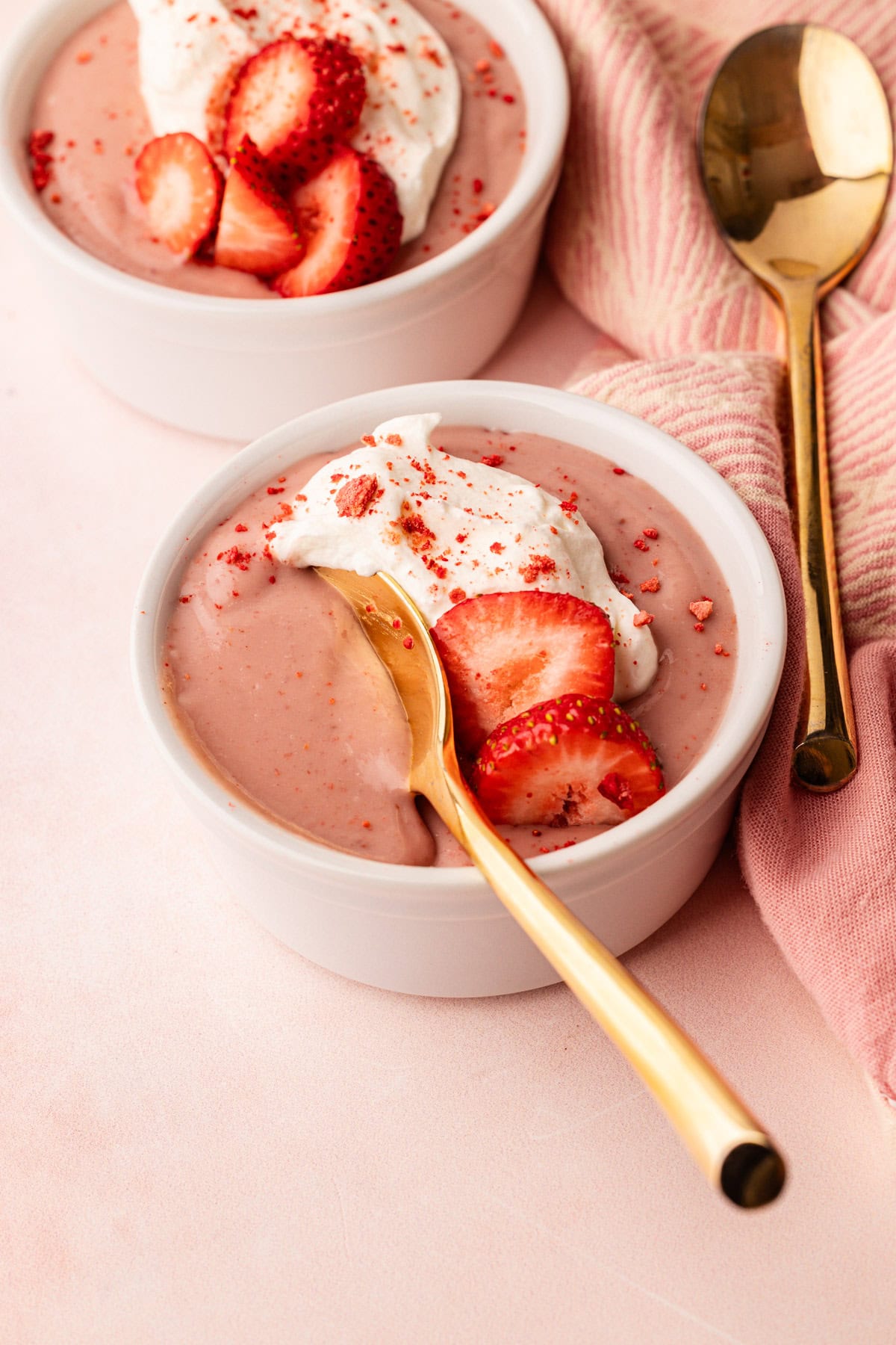 A serving of strawberry pudding with whipped cream and fresh sliced strawberries.