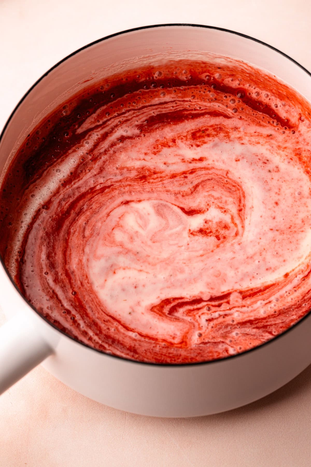 A strawberry cream mixture heating in a pot.