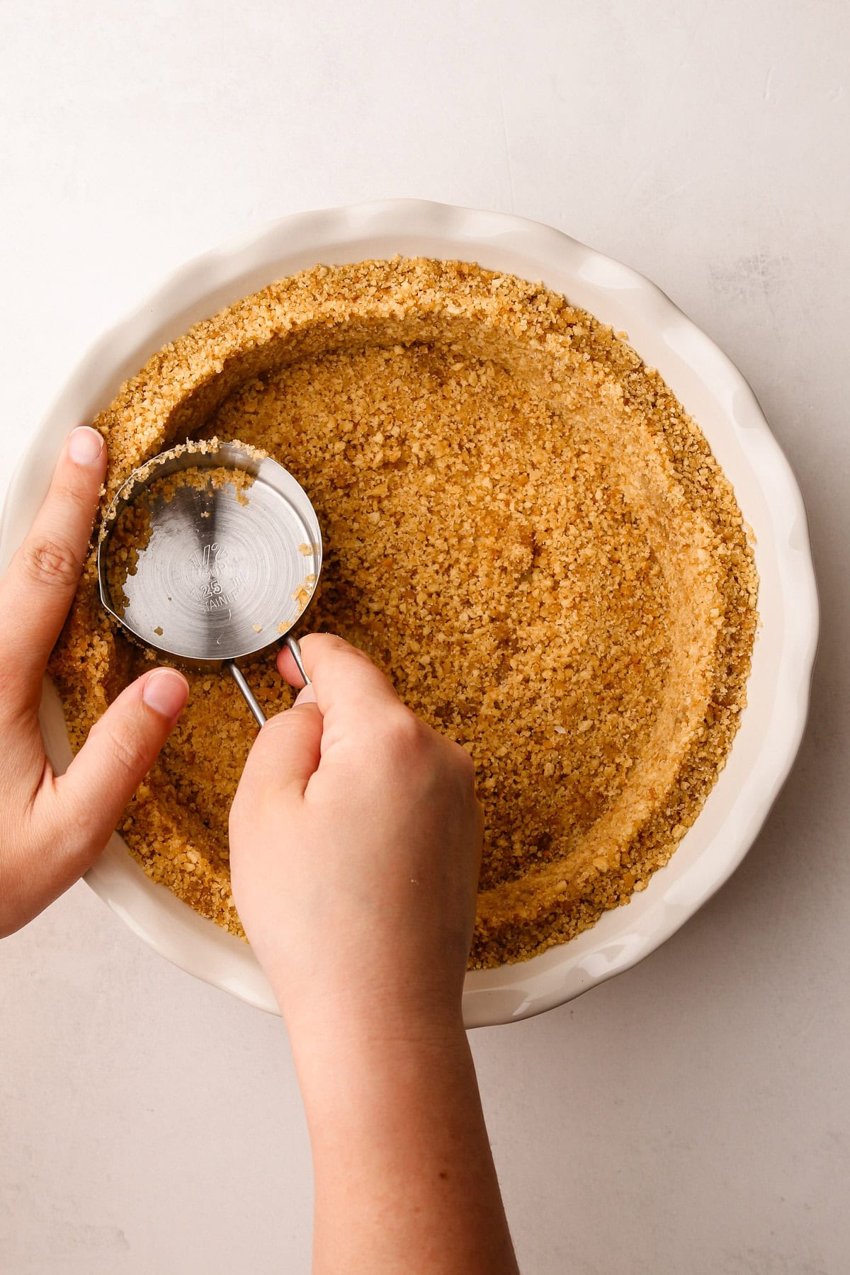 Forming a nilla wafer crumb crust with a measuring cup.