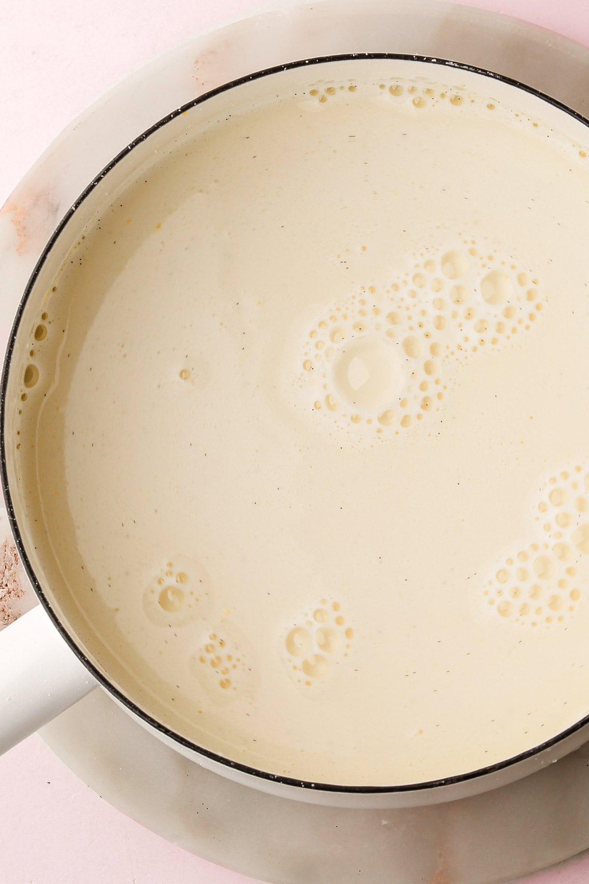 A white saucepan filled with the ingredients for pastry cream ready to be cooked.